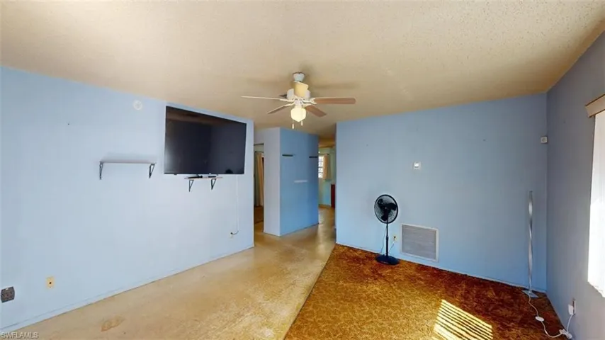 Unfurnished living room featuring a ceiling fan and a textured ceiling