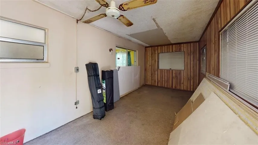 Den / flex room featuring light carpet, wooden walls, ceiling fan, and a textured ceiling