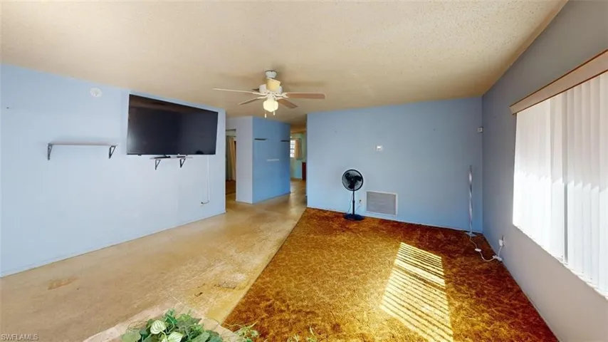 Unfurnished living room featuring a ceiling fan and a textured ceiling