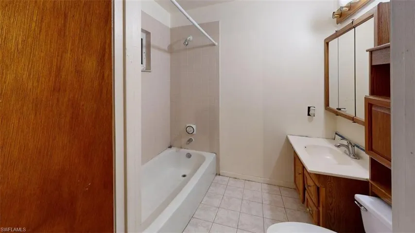 Full bath with vanity, light tile patterned floors, and  shower combination