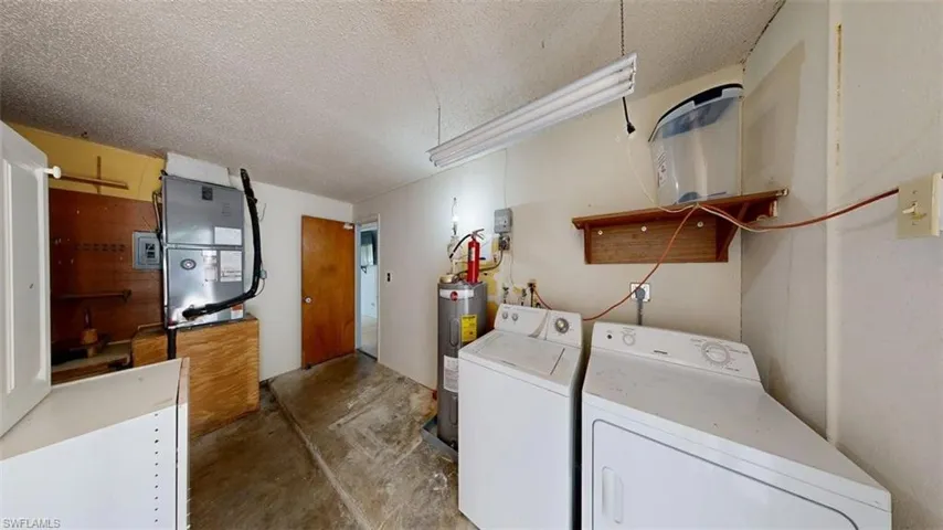 Laundry area with heating unit, unfinished concrete floors, washer and dryer, water heater, and a textured ceiling