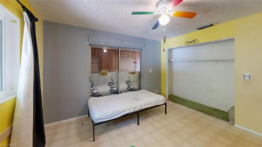 Bedroom with light floors, ceiling fan, a textured ceiling, and a closet