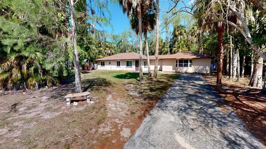Ranch-style house featuring asphalt driveway and a front lawn