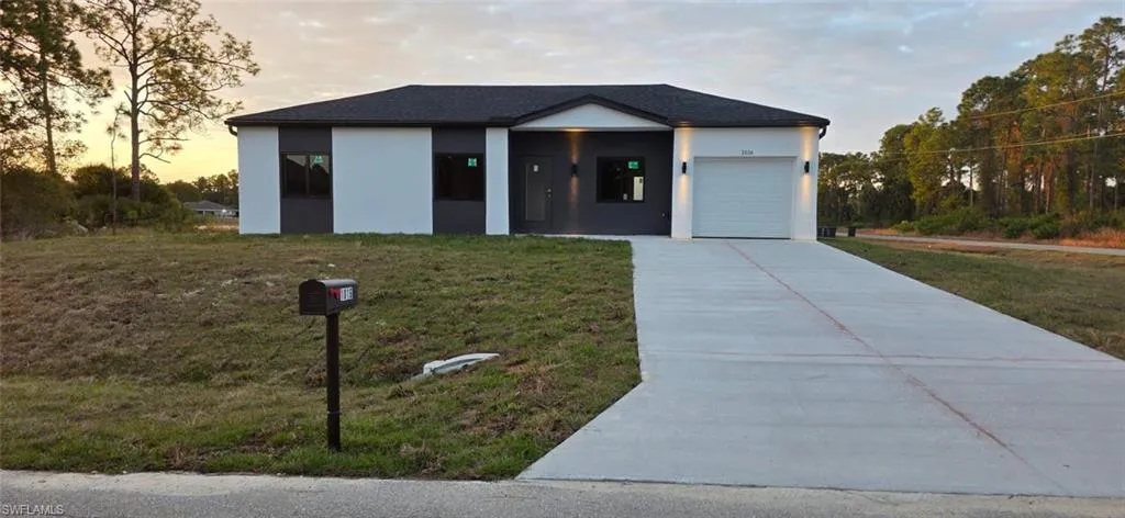 View of front of property with stucco siding, a front yard, driveway, and an attached garage