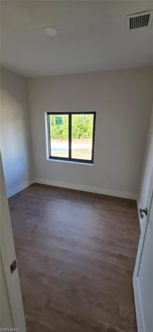Spare room with dark wood-style floors and baseboards