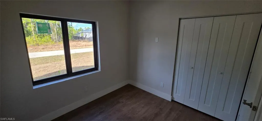 Unfurnished bedroom with dark wood-type flooring and a closet