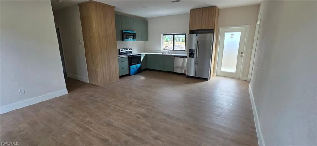 Kitchen with stainless steel appliances, dark wood-type flooring, light countertops, green cabinets, and modern cabinets