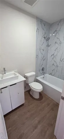 Bathroom featuring vanity, tub / shower combination, and dark wood-type flooring