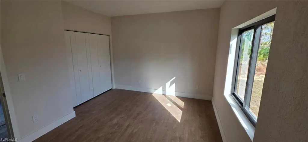 Unfurnished bedroom with dark wood-style flooring and a closet