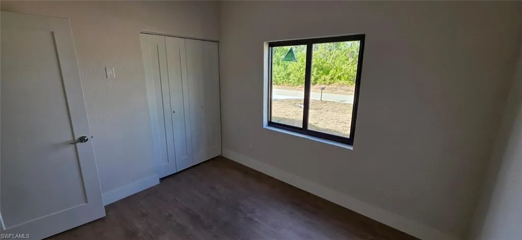 Unfurnished bedroom with dark wood-style flooring and a closet