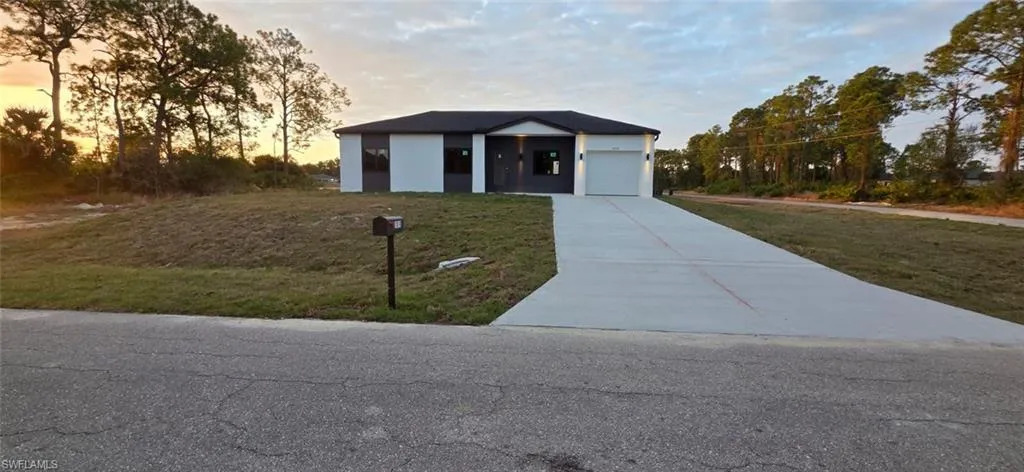 Contemporary house with driveway, a yard, an attached garage, and stucco siding