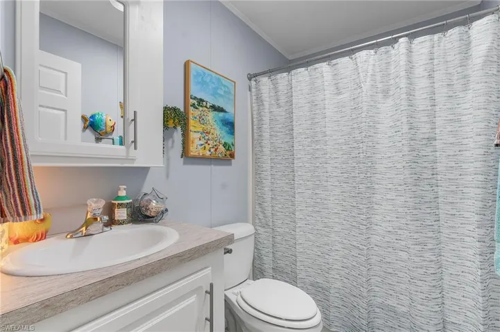 Bathroom with vanity, toilet, curtained shower, and ornamental molding