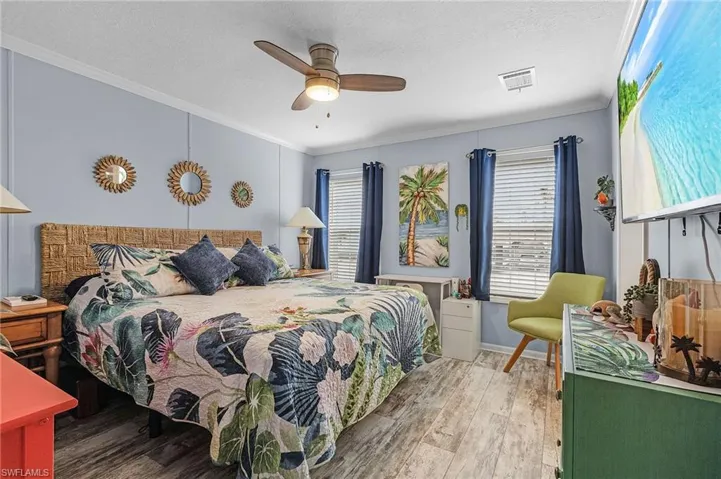Bedroom featuring hardwood / wood-style flooring, ceiling fan, ornamental molding, and a textured ceiling