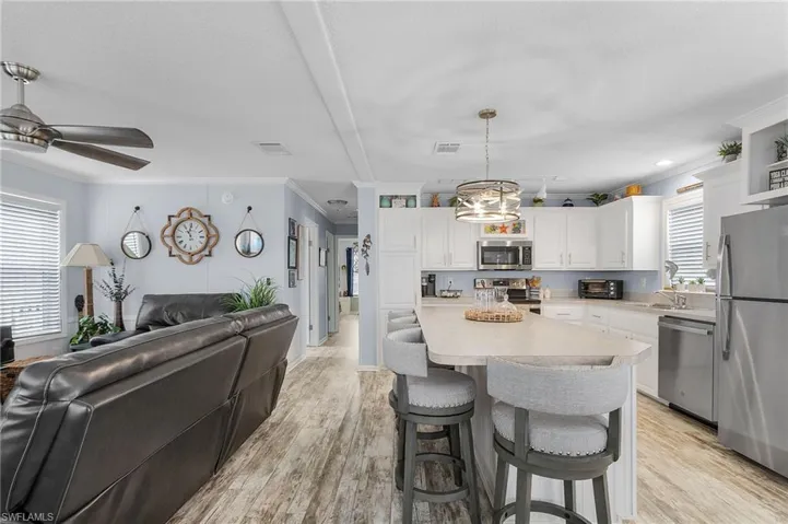 Kitchen featuring stainless steel appliances, a kitchen island, pendant lighting, light hardwood / wood-style flooring, and white cabinetry