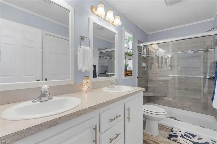 Bathroom featuring wood-type flooring, crown molding, toilet, a textured ceiling, and a shower with shower door
