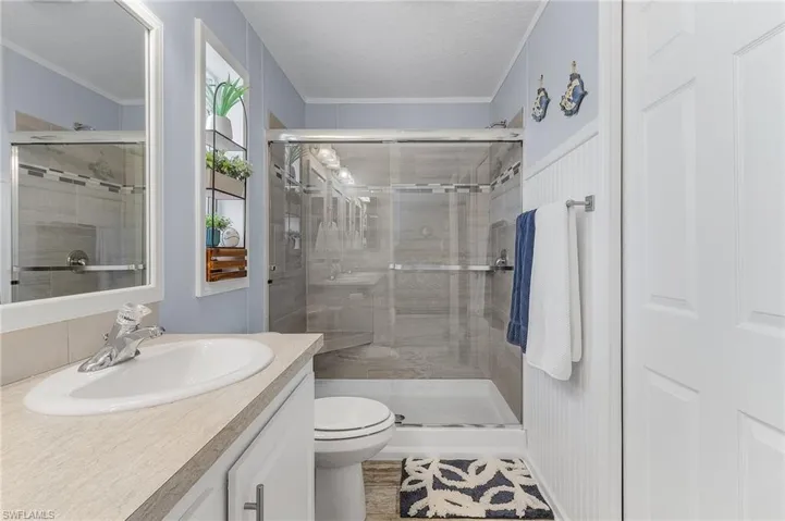 Bathroom featuring vanity, a textured ceiling, toilet, and a shower with shower door