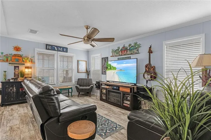 Living room featuring a textured ceiling, ceiling fan, light hardwood / wood-style floors, and crown molding
