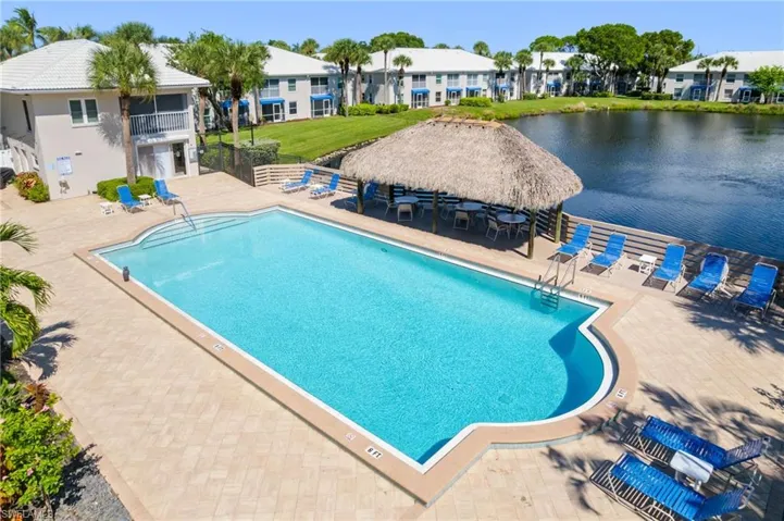 Community pool featuring a patio, gas grill, and a water view