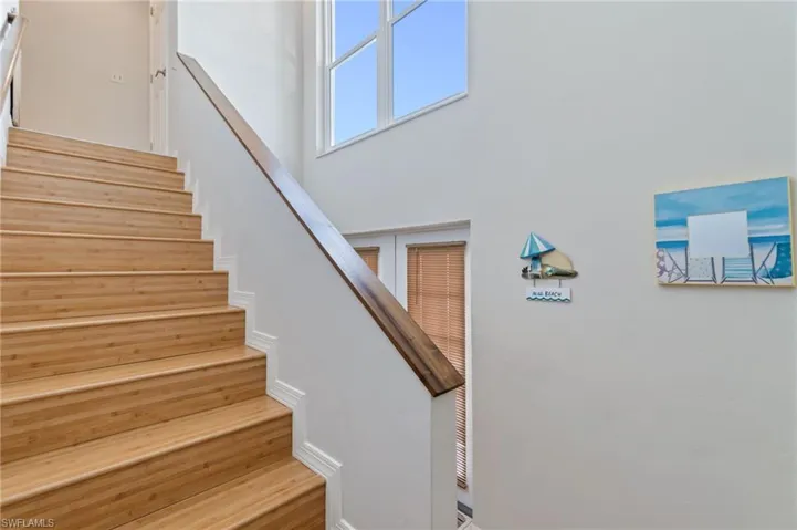 Stairway featuring wood finished floors and a towering ceiling
