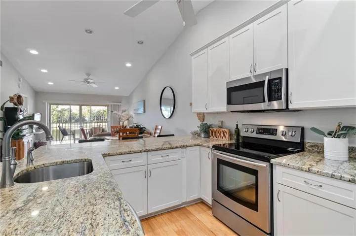 Kitchen with stainless steel appliances, white cabinets, recessed lighting, a peninsula, and light wood-style flooring