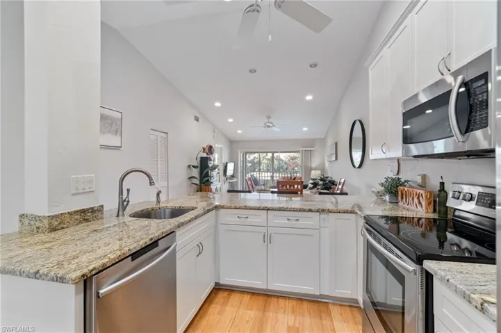 Kitchen featuring stainless steel appliances, white cabinetry, light wood-style flooring, light stone countertops, and recessed lighting