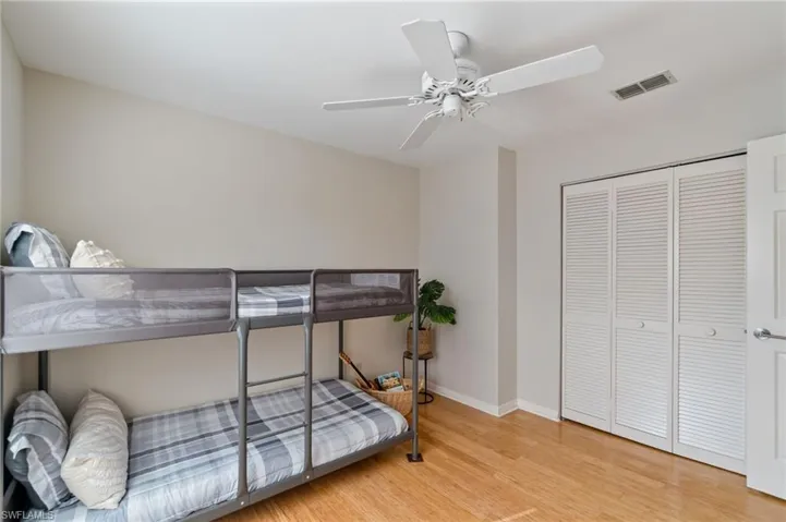 Bedroom with light wood-type flooring, a closet, and a ceiling fan