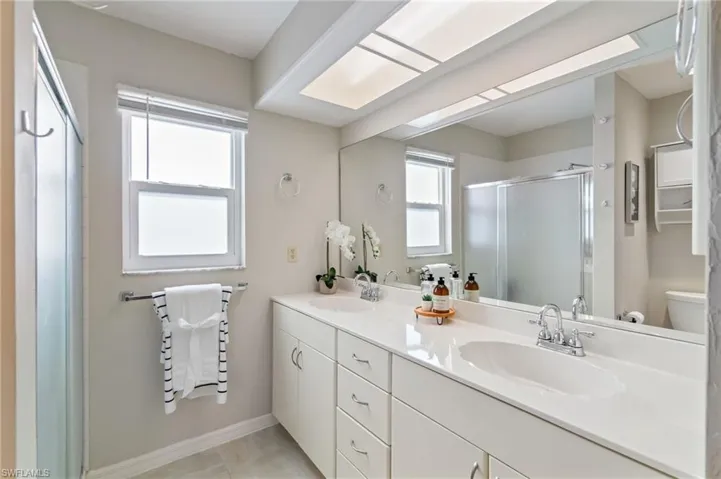 Bathroom featuring double vanity, a shower stall, and light tile patterned floors