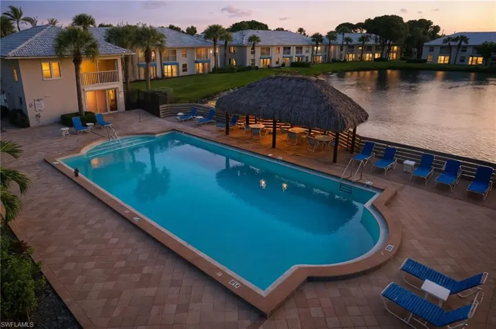 Pool at dusk featuring a community pool, a patio, and a balcony