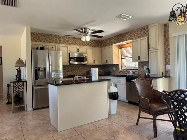 Kitchen featuring stainless steel appliances, a kitchen island, ceiling fan, and light tile patterned flooring