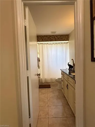 Full bath featuring vanity, light tile patterned floors, and shower / tub combo