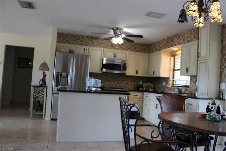 Kitchen featuring stainless steel appliances, a ceiling fan, light tile patterned flooring, a center island, and decorative light fixtures