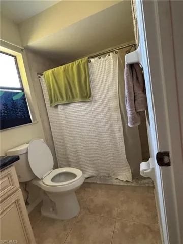 Full bath with a shower with shower curtain, light tile patterned floors, and vanity