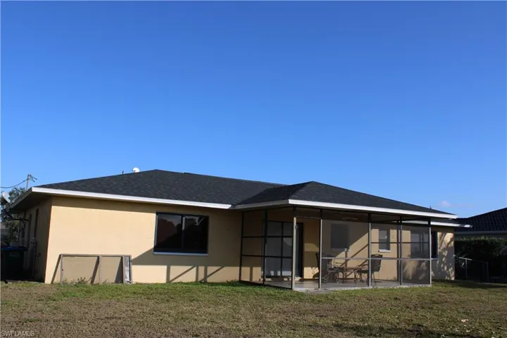 Back of property with a lawn, stucco siding, and a sunroom