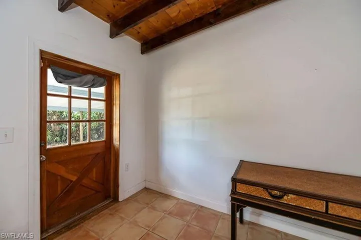 Entryway featuring light tile floors, lofted ceiling with beams, and wood ceiling