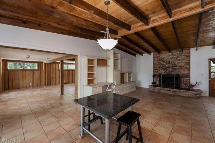 Unfurnished dining area with wooden ceiling, lofted ceiling with beams, a fireplace, and light tile floors