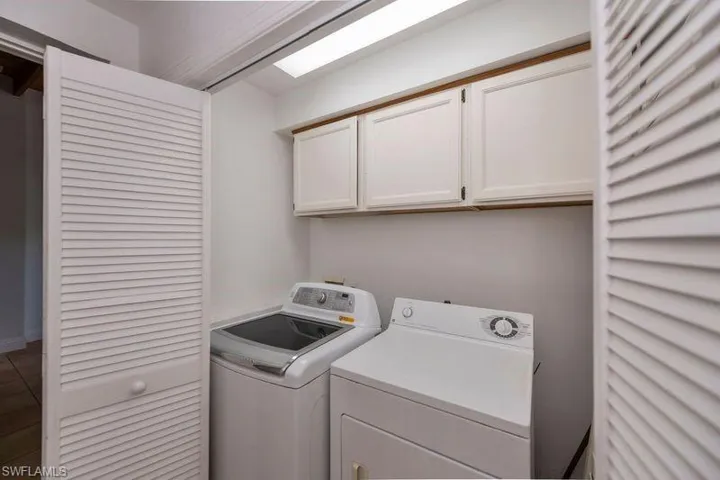 Clothes washing area with tile floors, independent washer and dryer, and cabinets