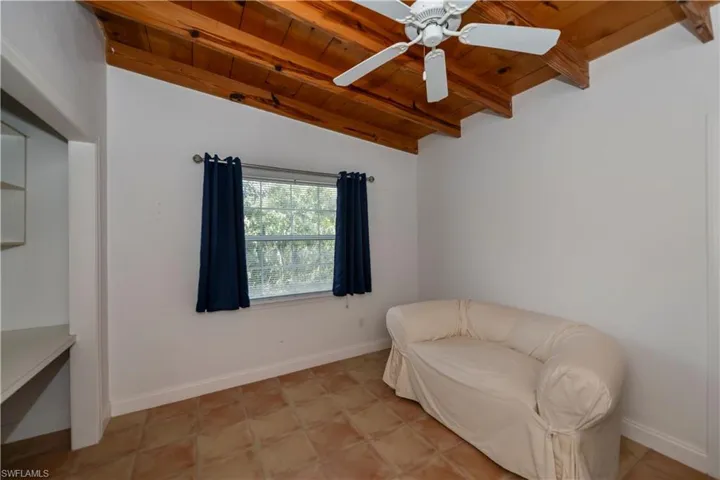 Sitting room featuring beamed ceiling, wooden ceiling, ceiling fan, and light tile floors