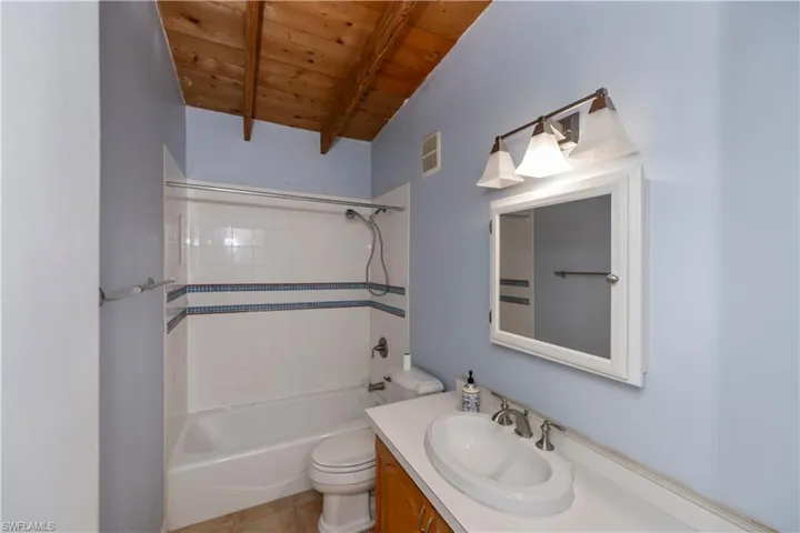 Full bathroom featuring tile flooring, wooden ceiling,  shower combination, vanity, and toilet