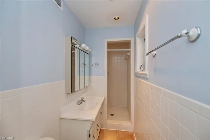 Bathroom featuring a shower with curtain, tile walls, backsplash, and large vanity