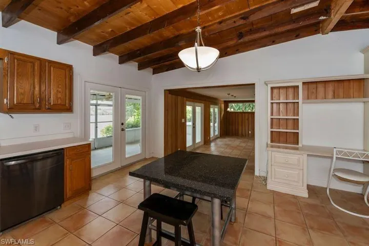 Kitchen with light tile flooring, dishwasher, hanging light fixtures, wooden ceiling, and french doors