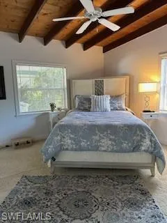 Carpeted bedroom featuring wooden ceiling, vaulted ceiling with beams, and ceiling fan