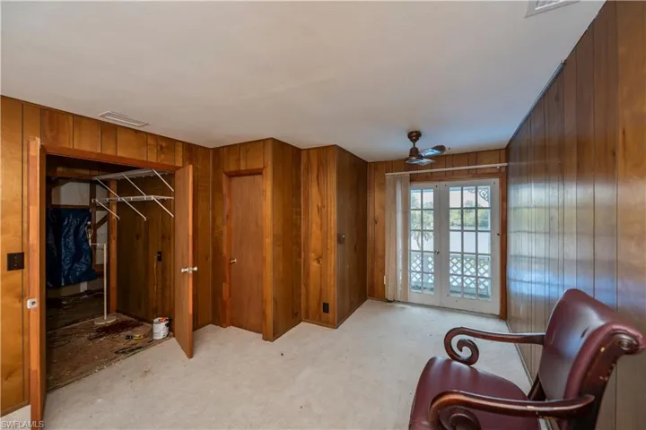 Sitting room featuring wooden walls, ceiling fan, and french doors