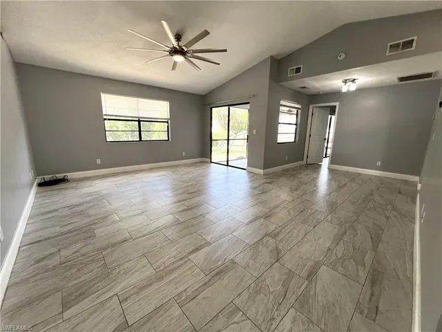 Unfurnished room with light tile flooring, ceiling fan, and vaulted ceiling