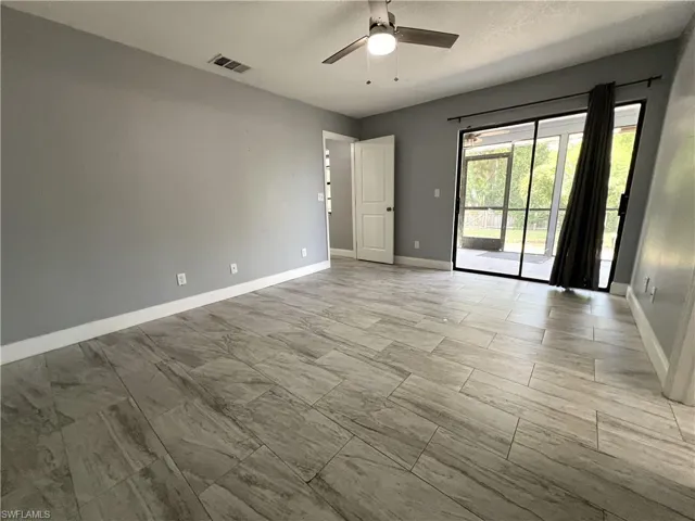 Unfurnished room with ceiling fan and light tile floors