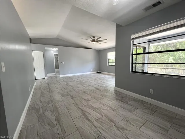 Unfurnished room featuring light tile floors, ceiling fan, and vaulted ceiling
