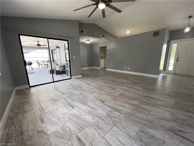 Empty room with ceiling fan, light tile flooring, and lofted ceiling