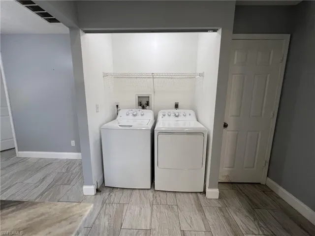 Clothes washing area featuring electric dryer hookup, washer hookup, light tile flooring, and washing machine and dryer