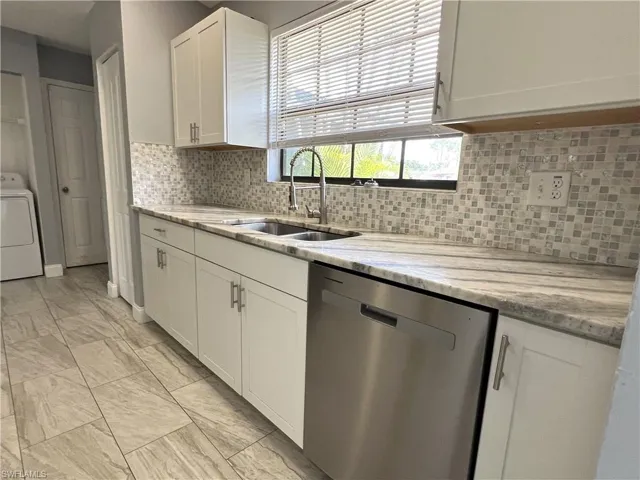 Kitchen with white cabinetry, backsplash, sink, and dishwasher