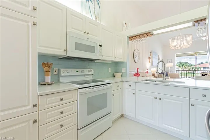 Kitchen with white appliances, a sink, a chandelier, and light countertops