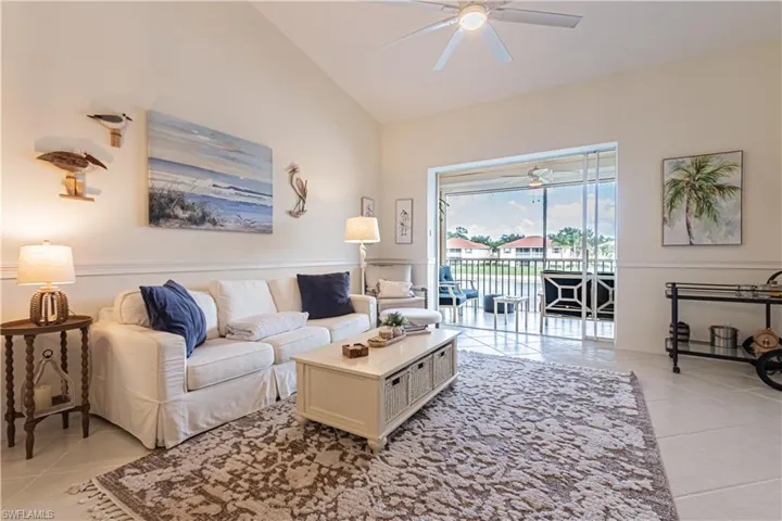 Living room with ceiling fan, light tile patterned floors, and high vaulted ceiling